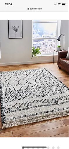 a room with a couch, chair and rug on the floor in front of a window