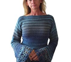 a woman wearing a blue sweater with crochet on the sleeves and shoulders, standing in front of a white background