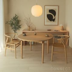 a table and chairs in a room with a painting on the wall above it, next to a potted plant