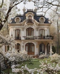 a large white house surrounded by trees and flowers