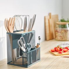 an organized kitchen utensil holder on a counter with tomatoes and other ingredients in the background