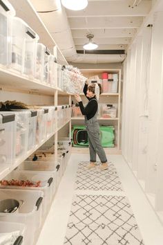 a woman is standing in the middle of a room with shelves full of plastic containers