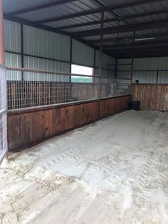 the inside of a horse barn with snow on the ground and fenced in area