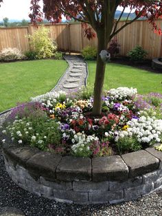 a flower bed in the middle of a yard next to a tree and grass area