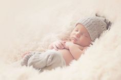 a baby sleeping on top of a white blanket wearing a knitted hat and mittens