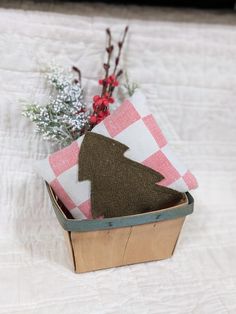 a small wooden box with fabric and flowers in it on a white bedcloth covered surface