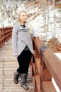 a woman is standing on a bridge in the snow with her hand on her hip