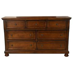 a wooden dresser with many drawers and knobs on the bottom drawer, against a white background