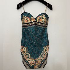 a bathing suit hanging on a hanger in front of a white wall with an orange and blue paisley print