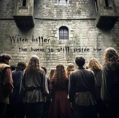 a group of people standing in front of a brick wall with writing on it that reads witch killer the human is still inside him