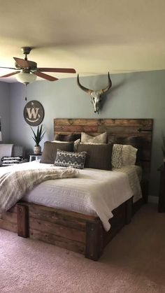 a bed room with a neatly made bed and a ceiling fan on the wall above it