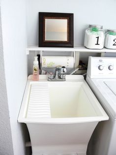 a white sink sitting under a mirror next to a washer and dryer