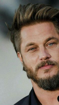 a close up of a person wearing a black shirt and tie with a goatee