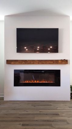 a fireplace with a flat screen tv above it and wood flooring on the side