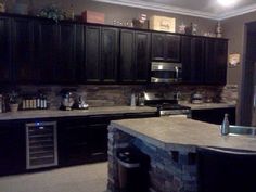 a large kitchen with black cabinets and granite counter tops, along with an island in the middle