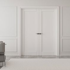 an empty white room with two chairs and a large door in the corner that leads to another room