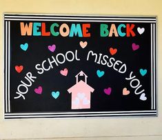 a welcome back sign on the side of a building with hearts around it and a church steeple