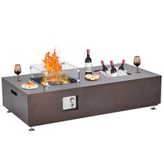 an outdoor fire pit with wine bottles and glasses on the top, in front of it