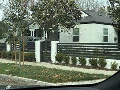 a white house with black fence and trees