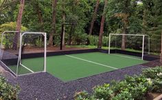 an outdoor tennis court surrounded by trees and bushes, with a goal on the ground