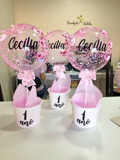 three balloons with pink bows are sitting on a table in front of some other balloons