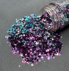 a jar filled with purple and blue glitter next to a small bottle full of confetti