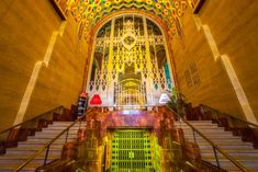 the inside of an ornate building with stairs and stained glass panels on the ceiling above