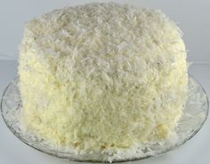 a close up of a cake on a plate with white frosting and shredded coconut