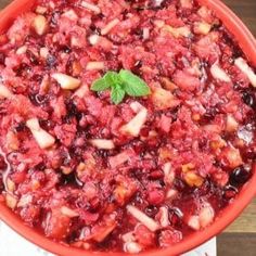 a bowl filled with cranberry sauce on top of a wooden table next to a napkin