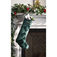 a green christmas stocking hanging from a mantel