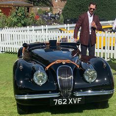 a man standing next to an old fashioned car