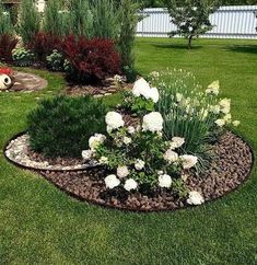 a flower bed in the middle of a lawn with white flowers and greenery around it