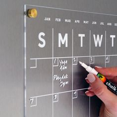 a person is writing on a calendar with a marker in their left hand and the words smtw written on it