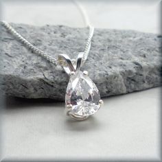 This sparkling pear shaped CZ pendant is a true stunner! Unusual shape and simple design. Cubic zirconia is a diamond alternative - wonderful for everyday wear and still get the sparkle without the cost. April's birthstone is a diamond and this would make a beautiful birthstone necklace. The pear shaped CZ pendant is 9x6 mm in size. Sterling silver setting and chain in your choice of length (see dropdown for options). Cubic zirconia is a synthesized (man-made) crystalline material that is hard a Letter Necklace Silver, Hummingbird Jewelry, Sand Dollar Necklace, October Birthstone Necklace, February Birthstone Necklace, Celtic Knot Necklace, Simple Silver Jewelry, Silver Wedding Jewelry, Peridot Pendant