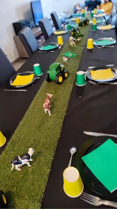 a table set with plates, cups and small dogs on the grass in front of them