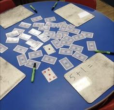 the table is covered with playing cards and crayons for numbers to match them