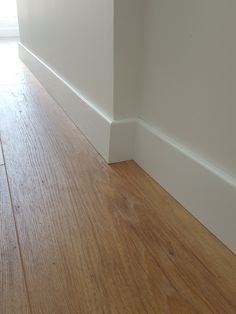 an empty room with white walls and wood flooring on one side, the wall is painted off