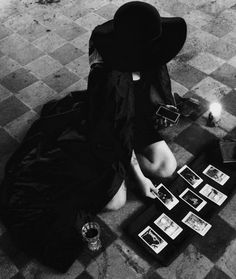 a woman sitting on the floor with pictures and candles in front of her, surrounded by photos