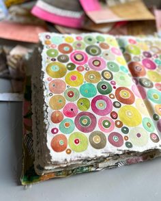 several different colored papers are stacked on top of each other with circles painted on them