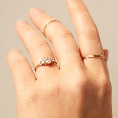 a woman's hand with two gold rings on top of her finger and one ring in the middle