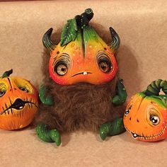 three painted pumpkins sitting next to each other on top of a cloth covered surface