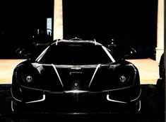 a black sports car parked in front of a building at night with lights shining on it