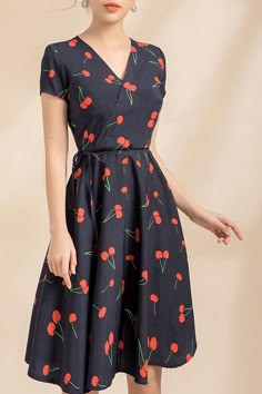 a woman in a dress with cherries on it is posing for the camera,