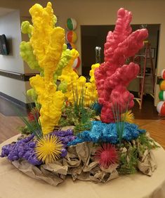 there are many different colored flowers on the top of this table in front of some balloons