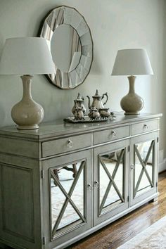 an image of a living room setting with lamps on the sideboard and mirrors above it