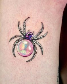 a spider tattoo on the leg with an orb in it's center and two claws