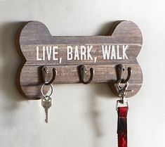 a dog bone shaped key holder with keys hanging from it's hooks and the words live, bark, walk