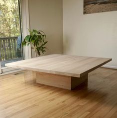 a wooden table sitting on top of a hard wood floor next to a large window