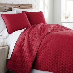 a bed with red bedspread and white pillows