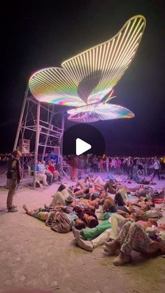 people are laying on the ground in front of a carnival ride at night with lights